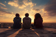 © Tidarat - young friends sitting together on rooftop at sunset on background