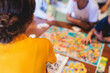 © tsuguliev - Process of playing board game and having fun with friends and family indoors, board game concept, group of kids children play board games at the table, roll the dice