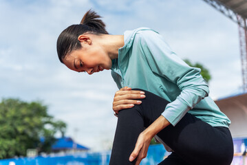 Close up asian woman runner athlete with muscle pain. Woman massaging Stretching, trauma injury while jogging outdoors. Fitness female sprain severe pain stretch pull. Leg muscle cramp calf sport.