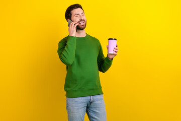 Poster - Photo of cheerful candid man wear stylish clothes hand hold cup tasty tea talk phone discuss rumor isolated on yellow color background