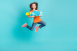 Photo of energetic cheerful girl wear stylish clothes have fun fly air hold water gun look empty space isolated on cyan color background