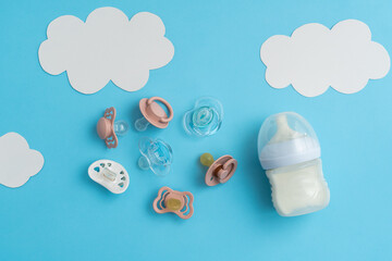 Newborn preparations: pacifiers and essentials on blue, top shot with space