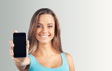 Wall Mural - Beautiful young woman holding blank screen smartphone