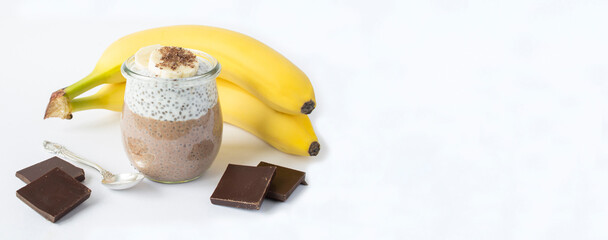 Wall Mural - Chocolate pudding with chia seed and banana in the glass jar on the white background. Copy space.