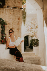 Wall Mural - Female tourist with paper city map on narrow streets of Ostuni, Italy