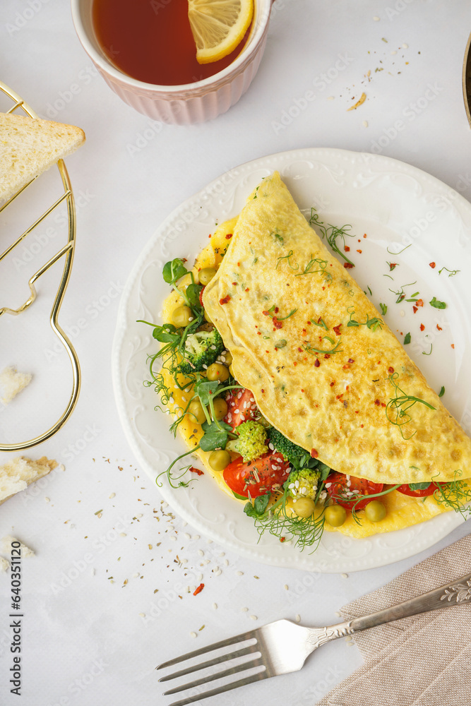 Tasty omelet with vegetables on light background
