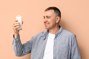 Poster - Mature man with glass of milk on beige background