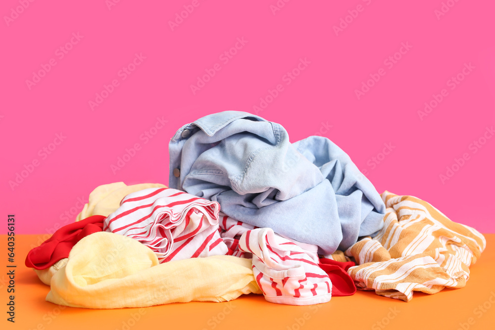 Pile of dirty laundry on orange table against pink background