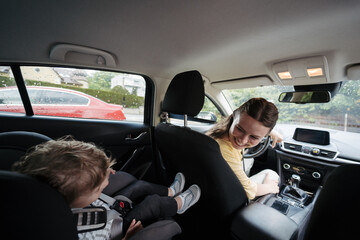 Mother checking her son before ride in car.