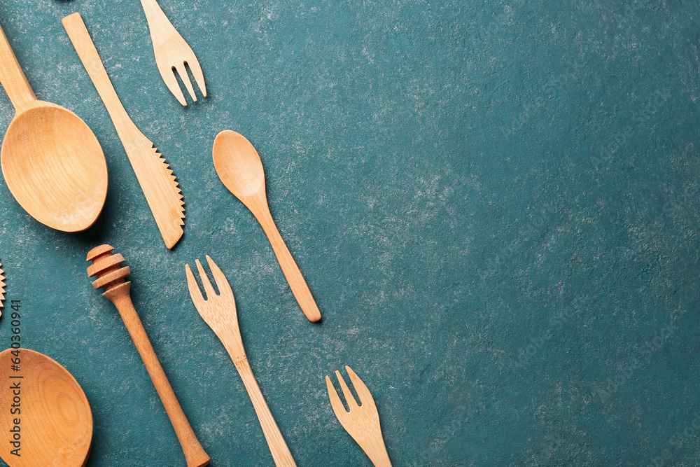 Different wooden kitchen utensils on green background