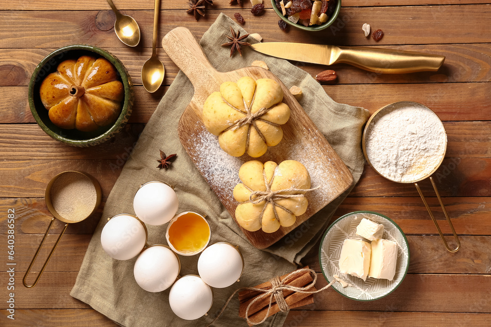 Board with pumpkin shaped buns and ingredients on wooden background