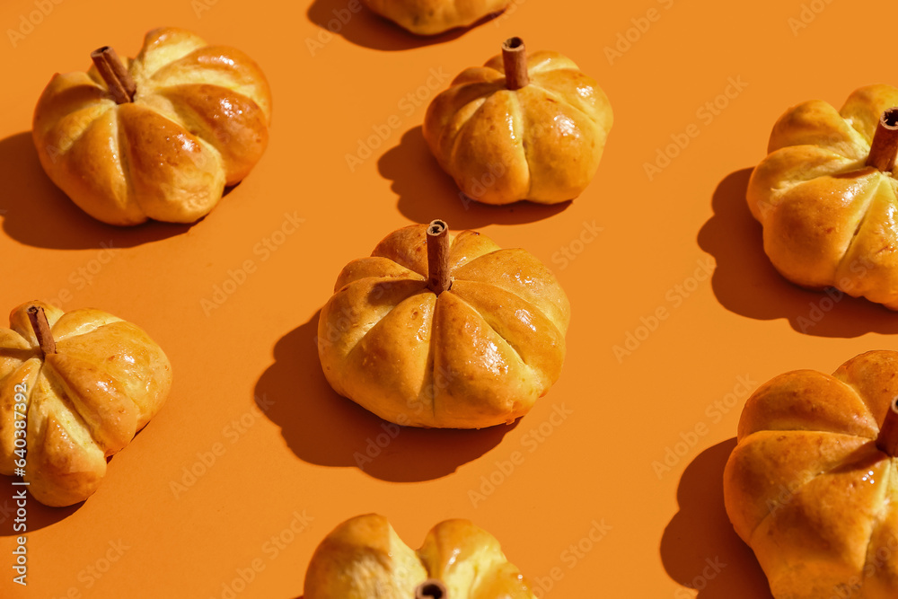 Tasty pumpkin shaped buns on orange background