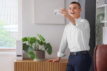 Canvas Print - Young man with mobile phone video chatting in office