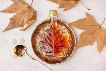 bottle of tasty maple syrup on light background