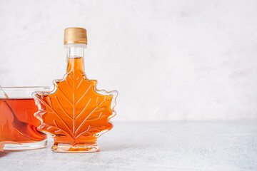 Wall Mural - Bottle and glass of tasty maple syrup on table