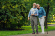 © New Africa - Senior man with walking cane and mature woman in park. Space for text
