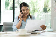 © ijeab - Smiling businesswoman talking on smartphone while waiting client in office