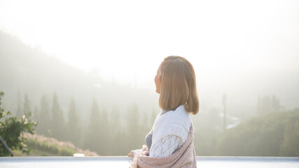 Wall Mural - asian woman stands with her back to camera and enjoys the view of forest. and looking mountain view in morning sunrise with copy space. trip and relaxing. Travel vacations and lifestyle concept.