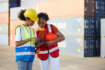 African factory workers or engineers working on tablet in containers warehouse storage