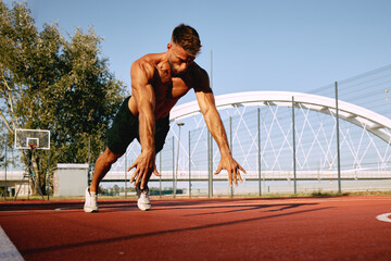 Wall Mural - Shirtless handsome man doing push-ups on the basketball court outside