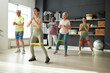 © AnnaStills - Elderly people exercising with rubber band together with instructor in health club
