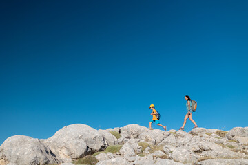 Wall Mural - .A woman and a child are walking along a mountain path