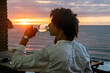© Cavan Images - latino man having a drink against sunset