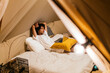 © Cavan Images - latin man watching a series on the computer lying on the bed in a tent