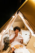 © Cavan Images - latino man with afro hair eating pizza in a tent of a camping