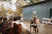 Little Girl Being Led On Pony Ride At Family Farm