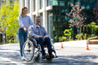 © zinkevych - Husband in wheelchair and loving wife walking in city street.