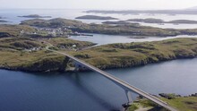 Retreating Drone Shot Of The Bridge Connecting Scalpay To The Isle Of Harris, Part Of The Outer Hebrides Of Scotland. The Minch Sea Is Visible As Well As Many Cliffs And Mountains.