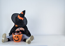 Little Girl Dressed As A Witch Looking For Candy In Her Halloween Basket, White Background