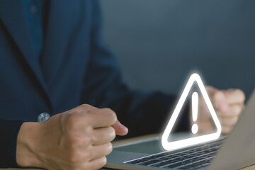 Wall Mural - businessman using laptop showing warning triangle and exclamation sign icon warning of dangerous pro