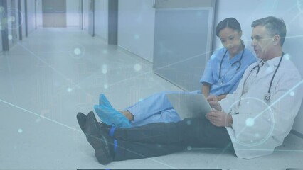 Canvas Print - Animation of connected dots over diverse doctors discussing report on laptop and sitting on floor