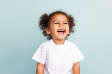 Little girl standing on pastel background, laughing out loud, wearing white nurse uniform