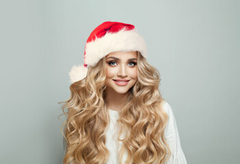 Wall Mural - portrait of cheerful blonde woman in santa hat smiling on white banner background, christmas model