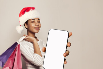 Wall Mural - Christmas portrait of perfect woman Santa with colorful shopper bags and smartphone with blank empty white screen display