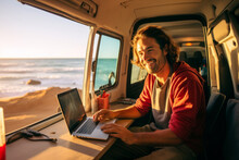 Handsome young digital nomad using a laptop computer in camper van on sunny day. Man working remotely with his laptop. Digital nomadic life.
