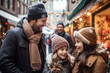 © MNStudio - Father and two children having wonderful time on traditional Christmas market on winter evening. Parent and kid enjoying themselves in Christmas town decorated with lights.
