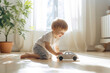 Cute toddler boy playing with white toy car. Small child having fun with toys. Kid spending time in a cozy living room at home.