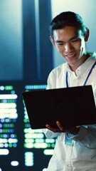 Poster - Vertical video Skillful employee wandering around data center infrastructure providing processing resources for different workloads. Asian admin doing checkup on servers tasked with solving