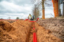 Network Cables In Red Corrugated Pipe Are Buried Underground On The Street. Underground Electric Cable Infrastructure Installation.