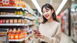 © Studio Nova - Smiling young woman with smart phone grocery shopping in supermarket