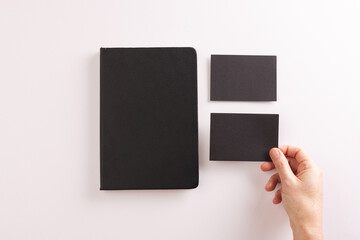 Black notebook and caucasian woman holding black paper card on white background