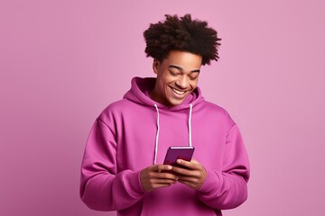 african boy wearing a pink sweatshirt holding a phone isolated on a pink background.generative ai