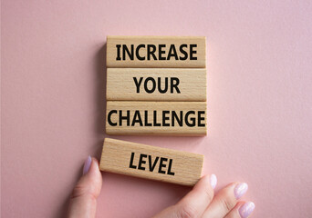 Challenge Level symbol. Concept word Increase your Challenge Level on wooden blocks. Beautiful pink background. Businessman hand. Business and Increase your Challenge Level concept. Copy space