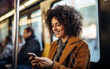 Happy curly African American woman passenger using smartphone on intercity bus