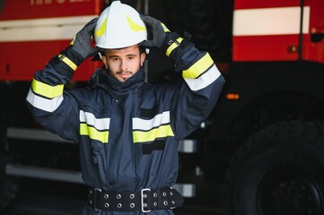 Wall Mural - Fireman (firefighter) in action standing near a firetruck. Emergency safety. Protection, rescue from danger.