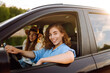 © maxbelchenko - Two women travelers travel by car, have fun. Beautiful female friends in the car enjoy a car trip together. Travel, tourism.